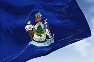 The US state flag of Maine waving in the wind. Concept of rapid detox in Maine.