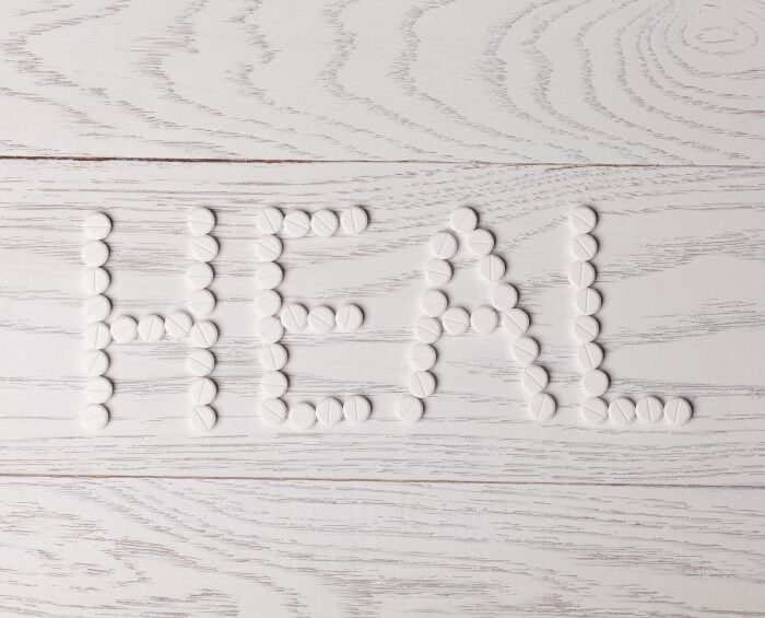 Word heal made of white pills on wooden table