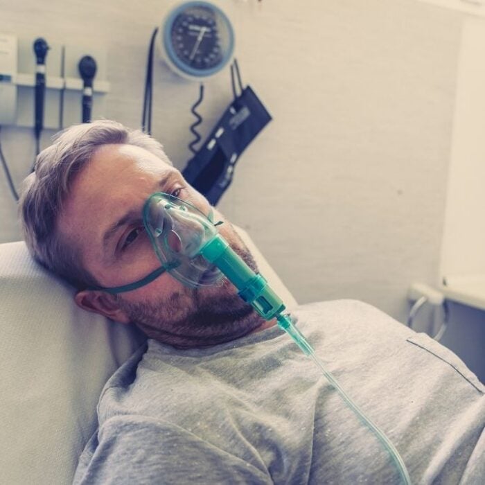 A man with oxygen mask in a hospital bed, concept of opioid intoxication