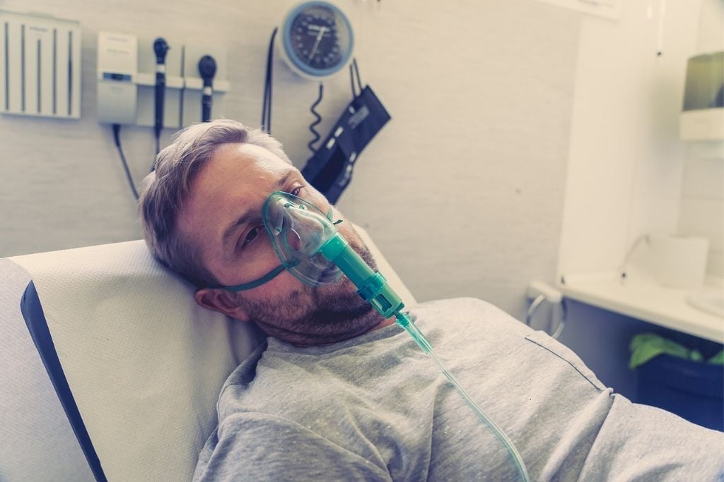 A man with oxygen mask in a hospital bed, concept of opioid intoxication