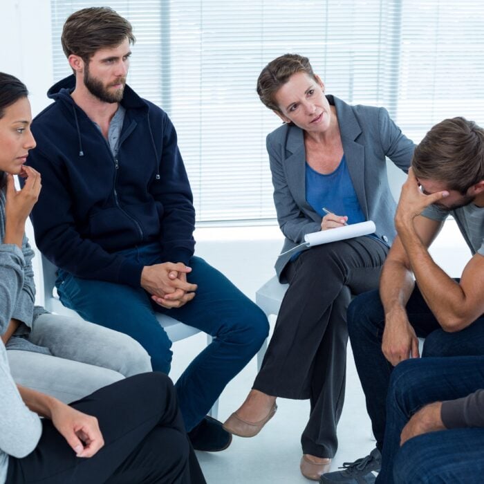 Concerned woman comforting another inopioid addiction rehab group at a therapy session