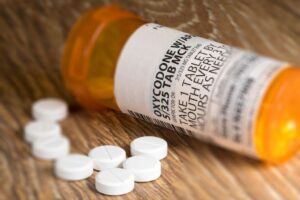 A close up photo of a prescription bottle for Oxycodone tablets and pills on wooden table. Concept of how to get off percocet safely.