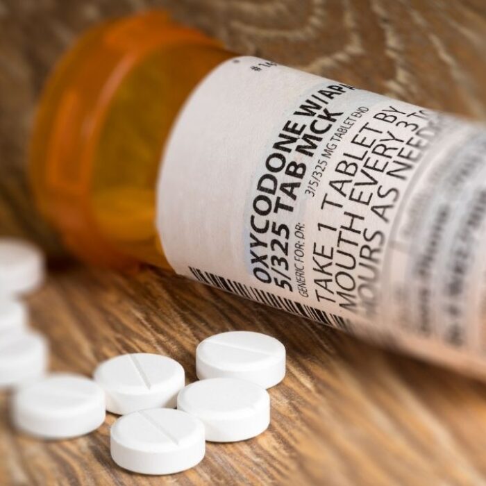 A close up photo of a prescription bottle for Oxycodone tablets and pills on wooden table. Concept of how to get off percocet safely.