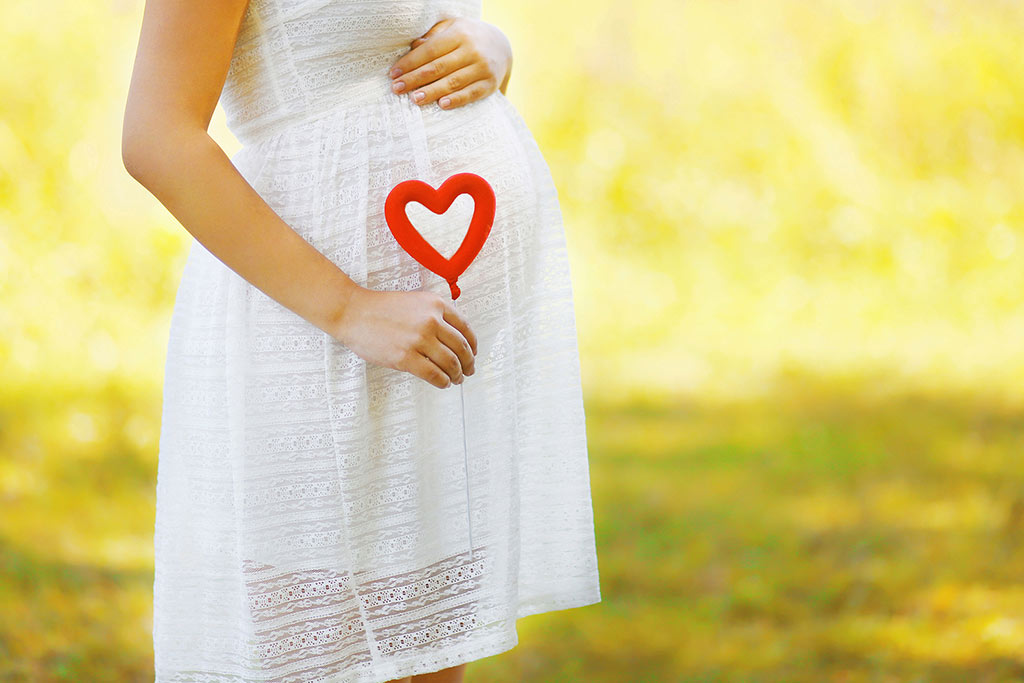 Quitting fentanyl during pregnancy concept - pregnant woman and heart symbol outdoors in sunny summer day