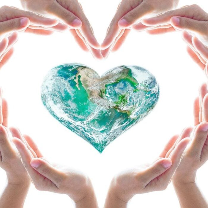 A photo of hands coming together in a shape of a heart around heart-shaped globe - concept of addressing the fentanyl crisis amidst modern challenges