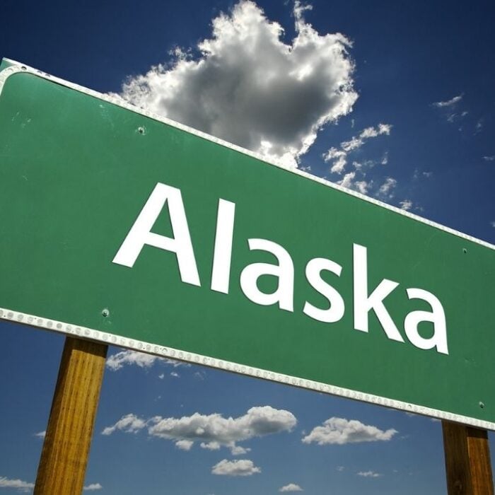 Photo of Save Download Preview Alaska Road Sign with dramatic clouds and sky. Concept of Alaska detox.