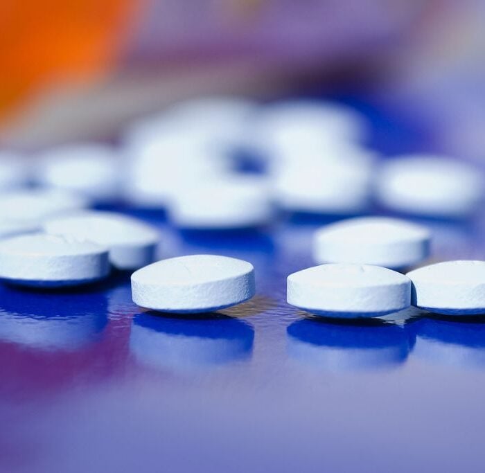 Bottle of spilled out prescriptions pills on a blue background, concept of Percocet vs fentanyl