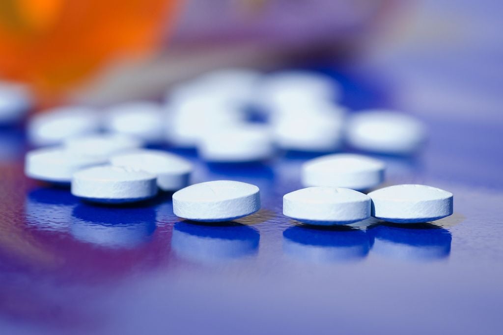 Bottle of spilled out prescriptions pills on a blue background, concept of Percocet vs fentanyl